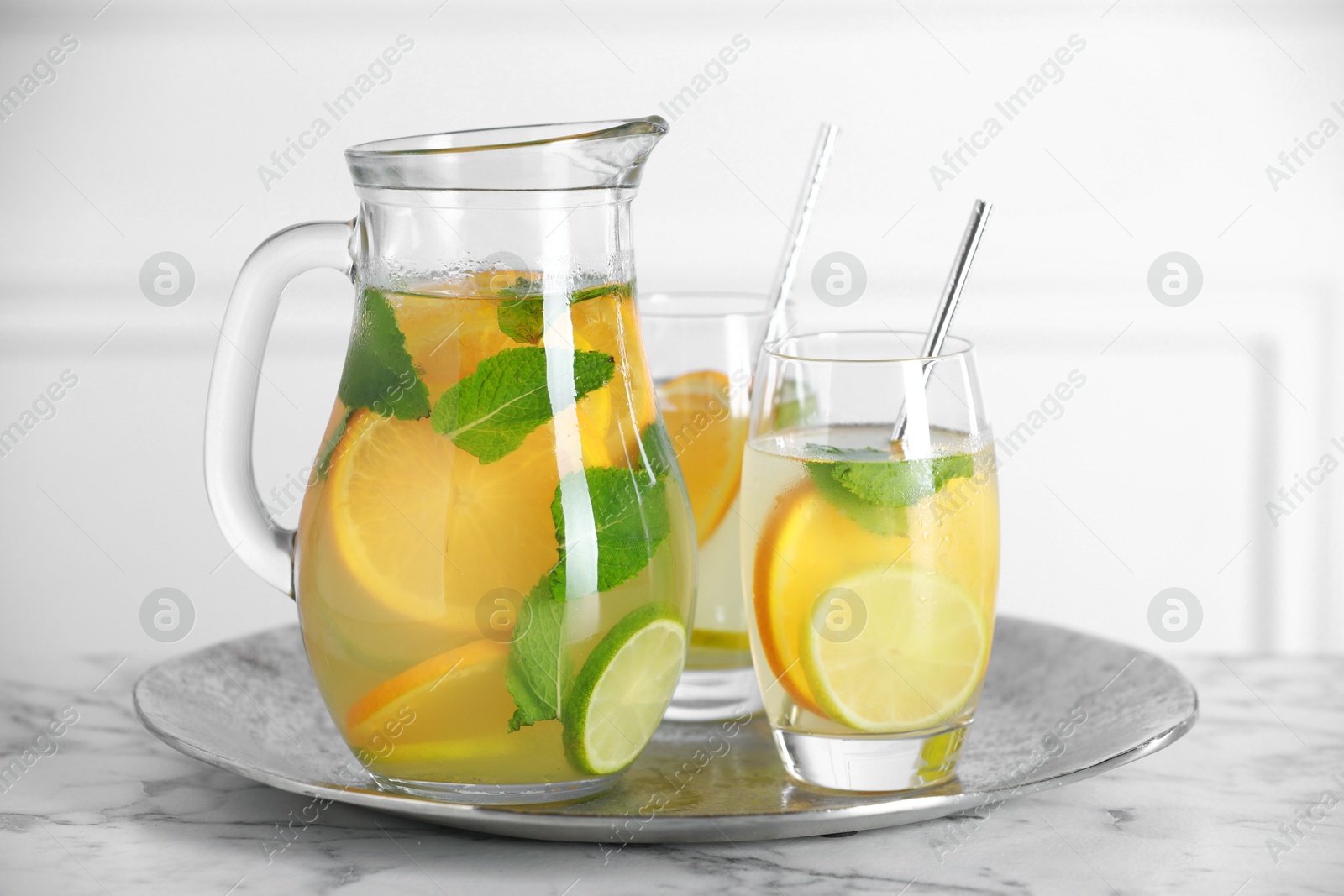 Photo of Freshly made lemonade with mint in jug and glasses on white marble table