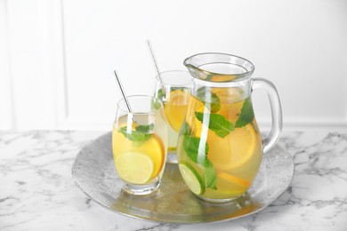 Photo of Freshly made lemonade with mint in jug and glasses on white marble table