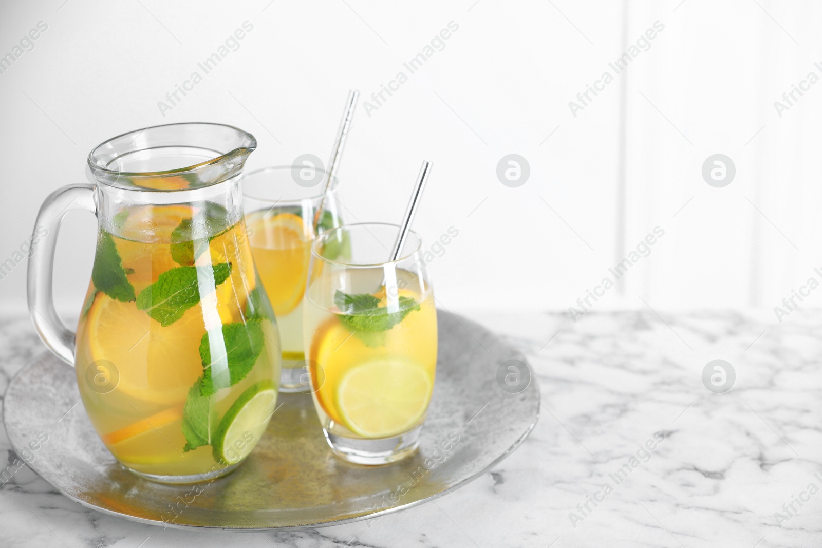 Photo of Freshly made lemonade with mint in jug and glasses on white marble table