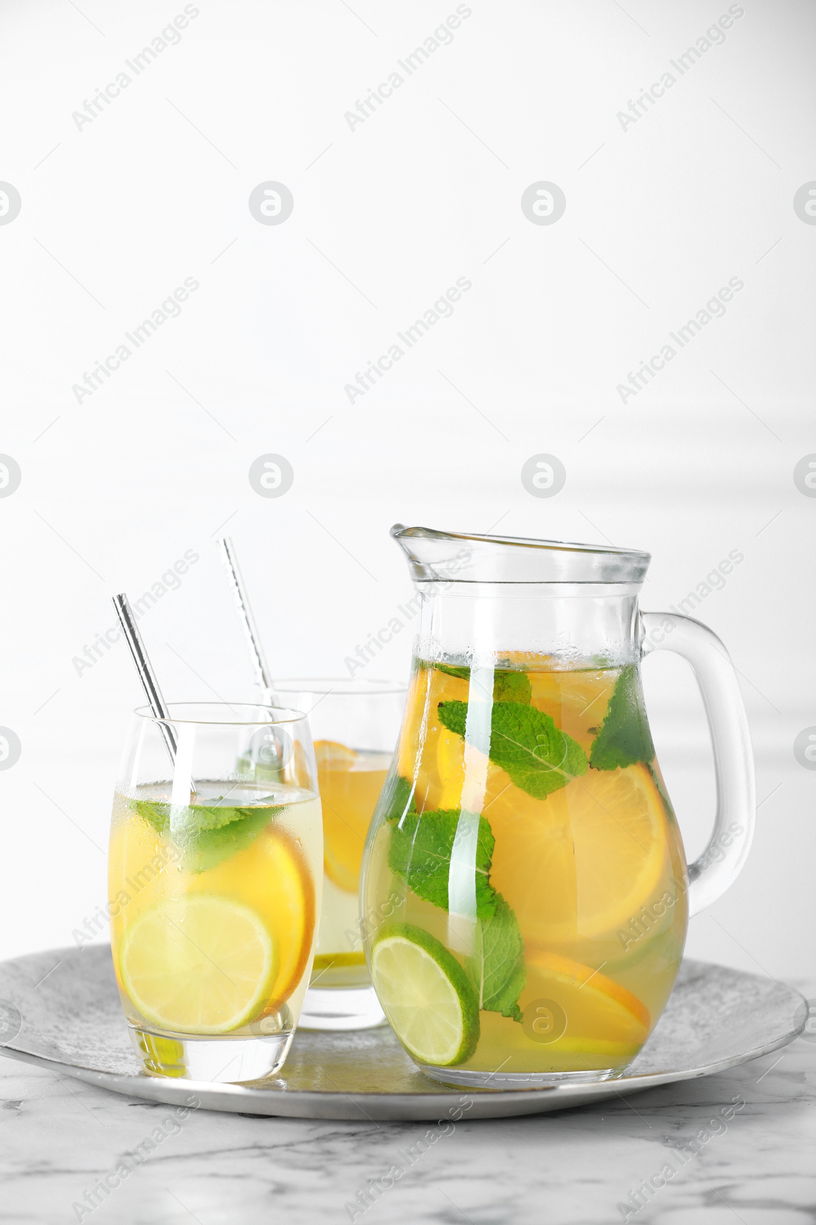 Photo of Freshly made lemonade with mint in jug and glasses on white marble table