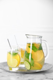 Photo of Freshly made lemonade with mint in jug and glasses on white marble table