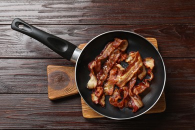 Photo of Delicious bacon slices in frying pan on wooden table, top view