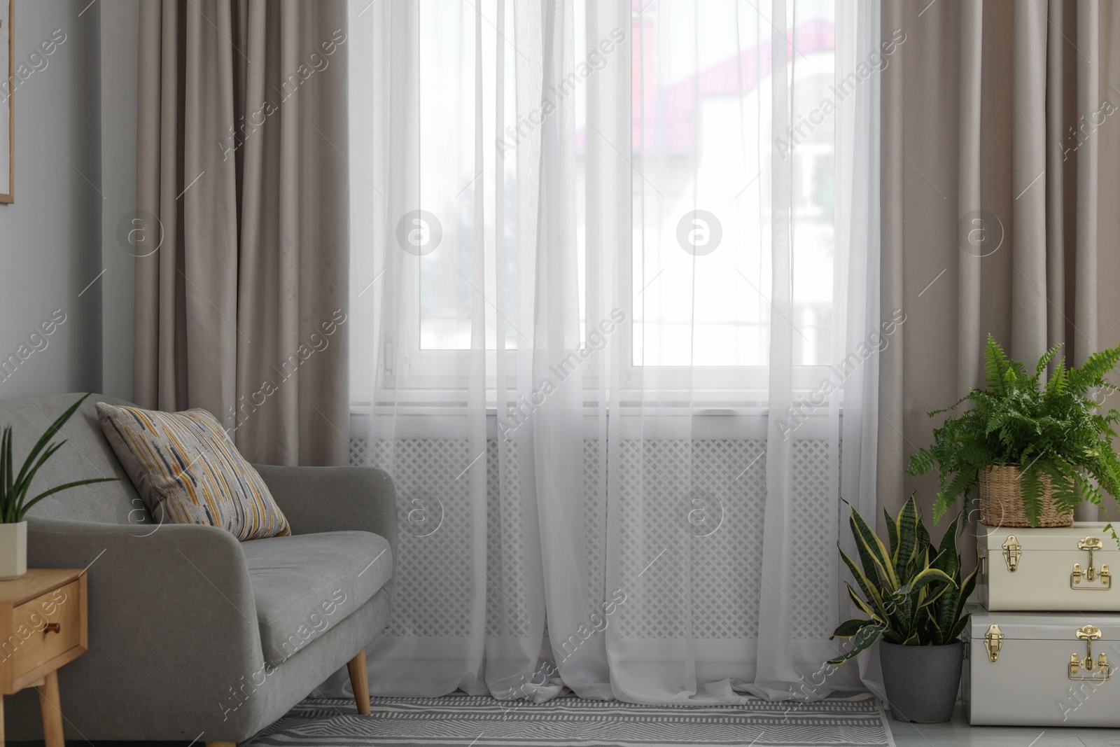 Photo of Comfortable sofa and elegant curtains in living room. Interior design