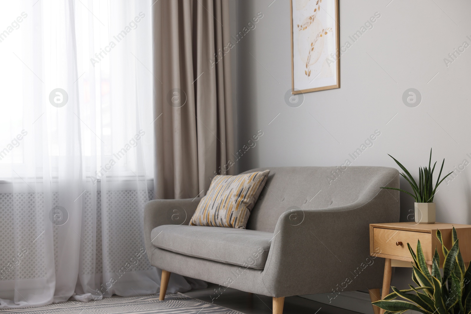 Photo of Comfortable sofa and elegant curtain in living room. Interior design