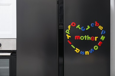 Word Mother and heart made of many bright magnetic letters on fridge indoors. Learning alphabet