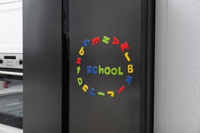 Word School and circle made of many bright magnetic letters on fridge indoors. Learning alphabet