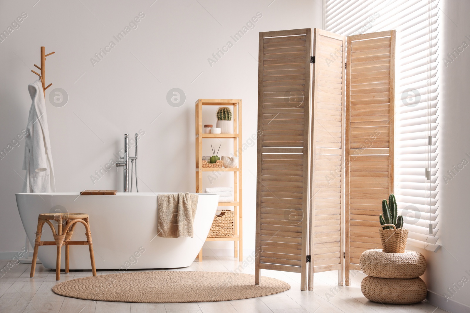 Photo of Wooden folding screen, bathtub, chair and rack in bathroom