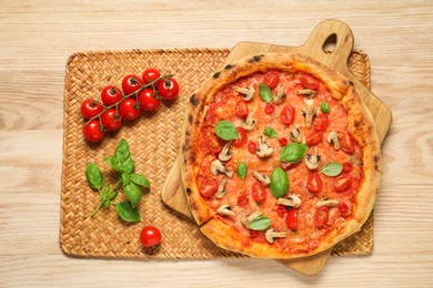 Delicious pizza with tomatoes, mushrooms and basil on wooden table, top view