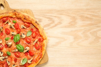 Photo of Delicious pizza with tomatoes, mushrooms and basil on wooden table, top view. Space for text