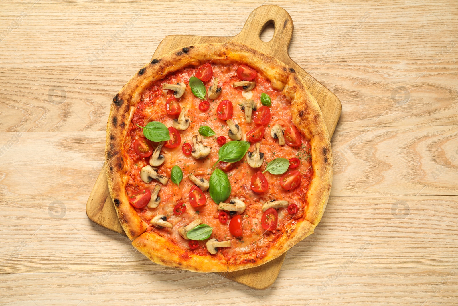 Photo of Delicious pizza with tomatoes, mushrooms and basil on wooden table, top view.