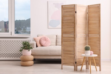 Wooden folding screen, sofa, table and houseplants in living room