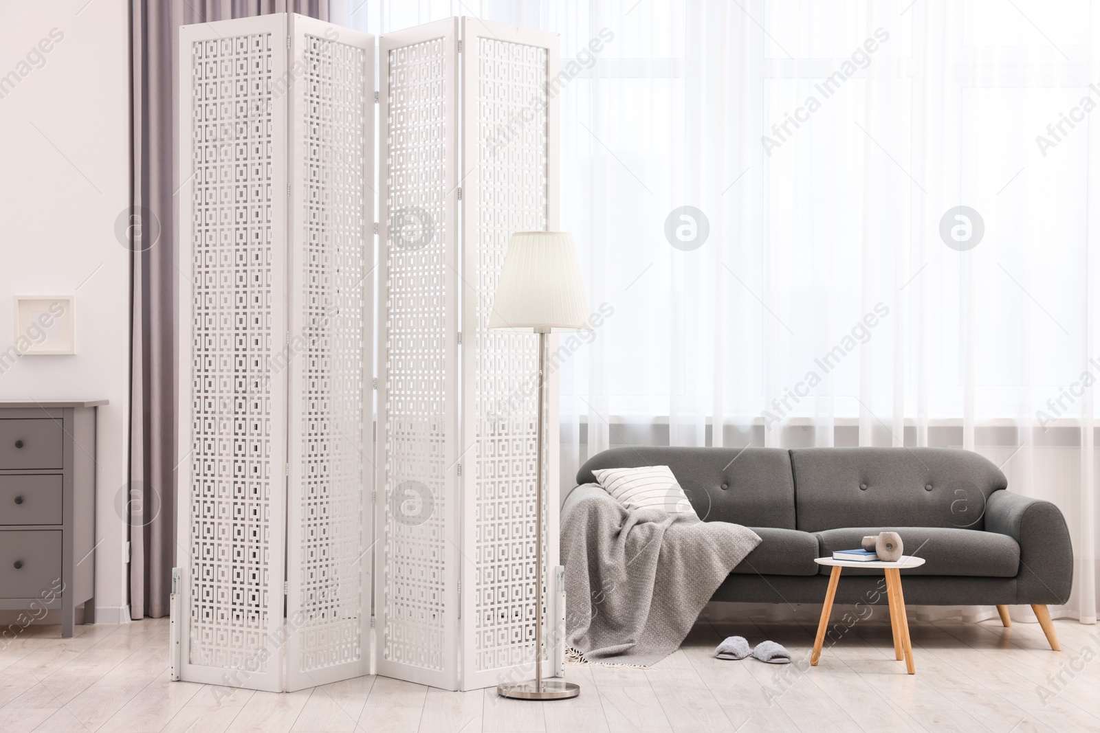 Photo of White folding screen, sofa, side table and lamp in living room