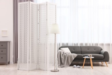 White folding screen, sofa, side table and lamp in living room