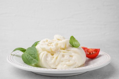 Photo of Delicious burrata cheese, tomatoes and basil on light table, closeup. Space for text