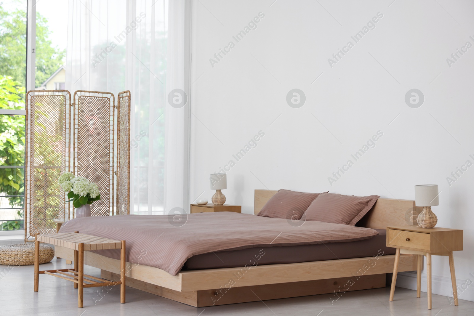 Photo of Folding screen, comfortable bed, ottoman and bedside tables in room