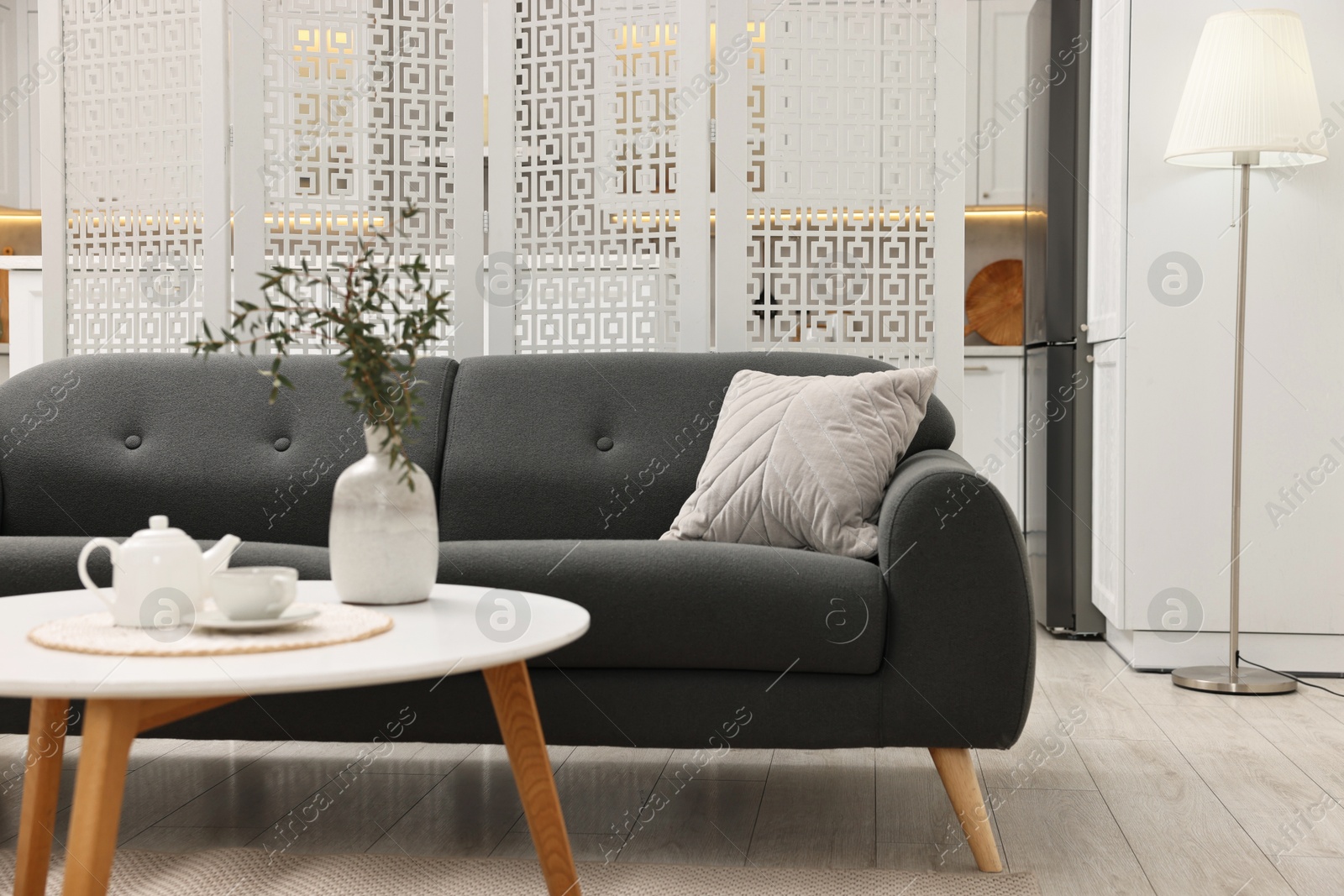 Photo of Stylish room interior with table, sofa and folding screen