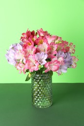 Beautiful alstroemeria flowers in vase on green background