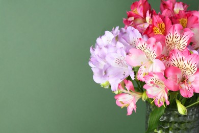 Photo of Beautiful alstroemeria flowers in vase on green background, closeup. Space for text