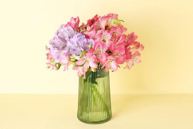 Photo of Beautiful alstroemeria flowers in vase on beige background