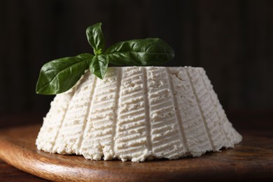 Photo of Tasty ricotta (cream cheese) and basil on wooden table, closeup