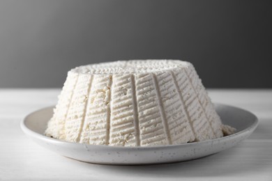 Photo of Tasty ricotta (cream cheese) on white wooden table, closeup