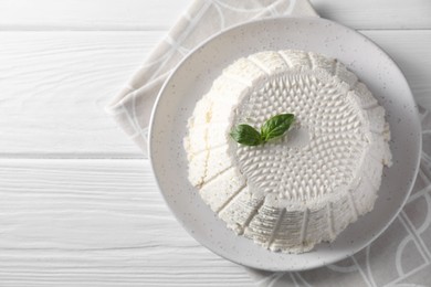 Photo of Tasty ricotta (cream cheese) and basil on white wooden table, top view. Space for text