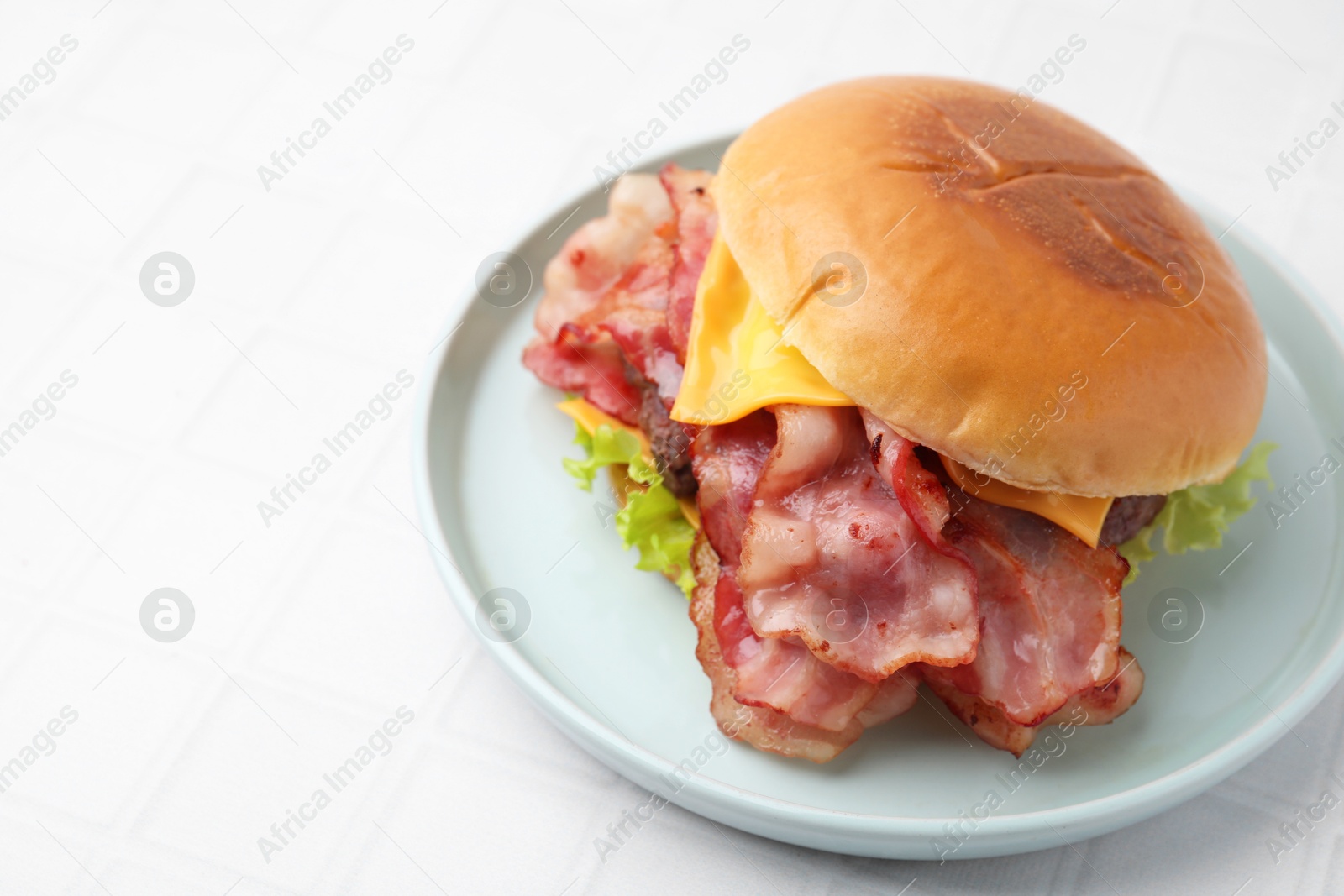 Photo of Delicious burger with bacon, patty and cheese on white tiled table, space for text