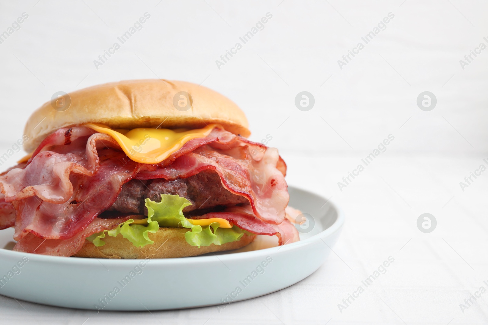 Photo of Delicious burger with bacon, patty and cheese on white table