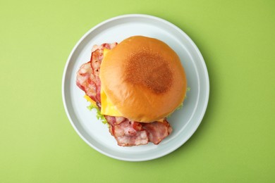 Photo of Delicious burger with bacon and cheese on green background, top view