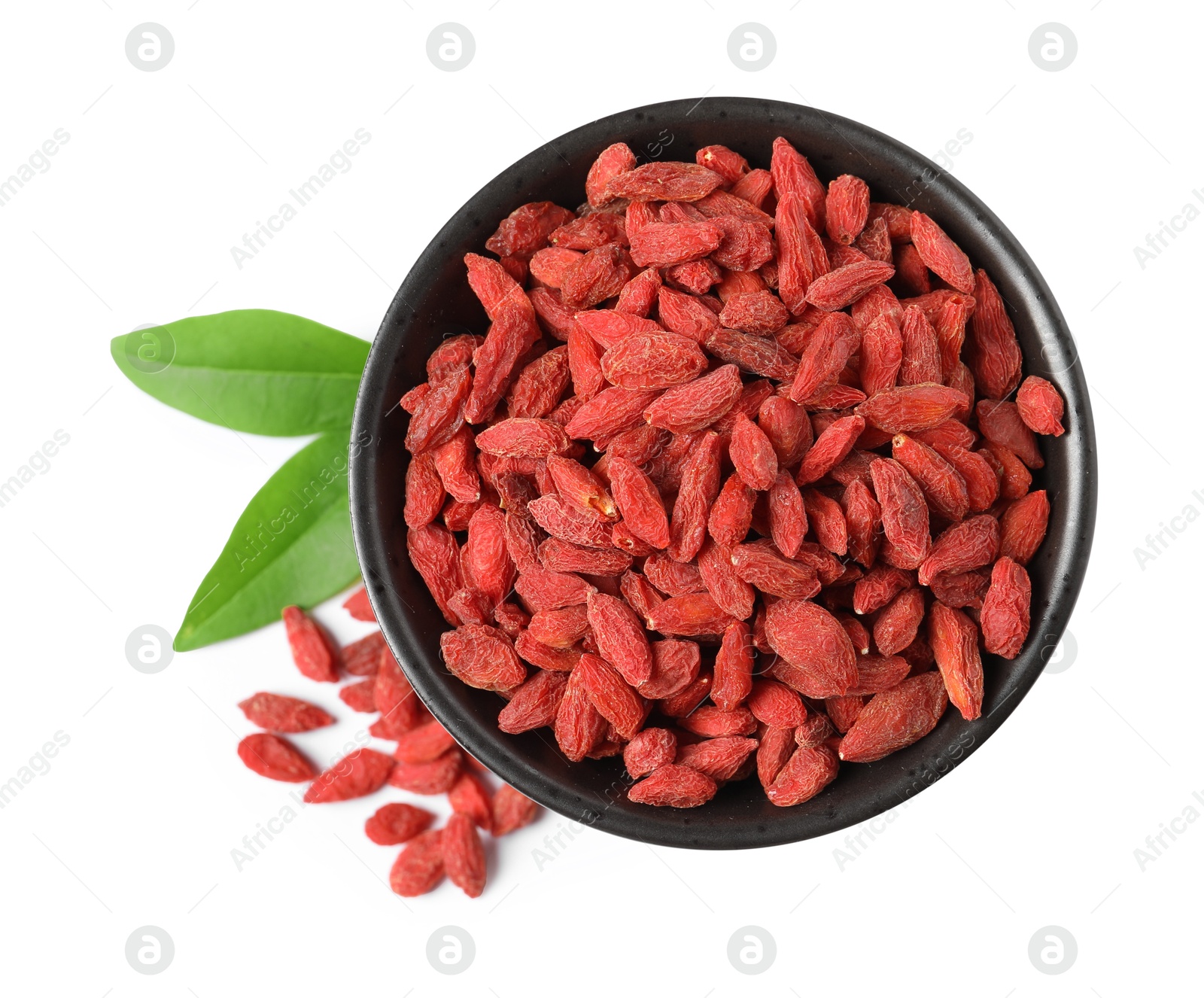 Photo of Dried goji berries in bowl and leaves isolated on white, top view