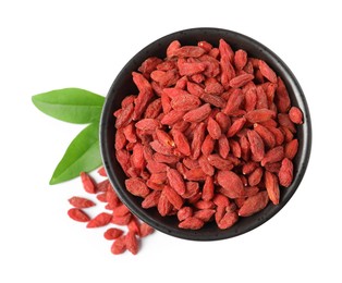 Photo of Dried goji berries in bowl and leaves isolated on white, top view