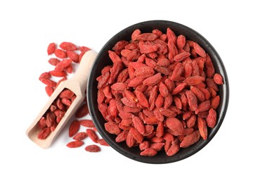 Photo of Dried goji berries in bowl and scoop isolated on white, top view