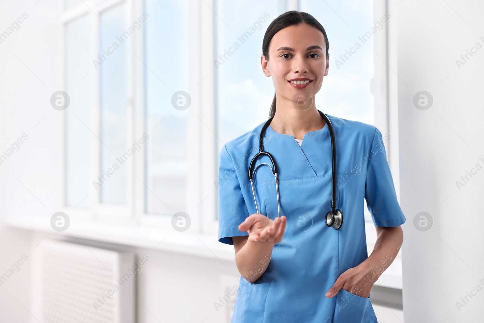 Photo of Smiling nurse holding something in clinic. Space for text