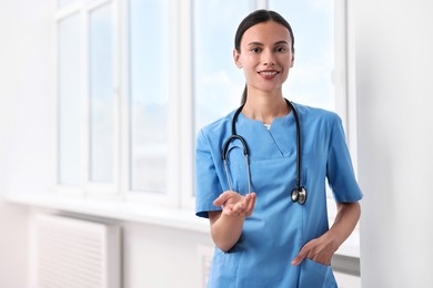 Photo of Smiling nurse holding something in clinic. Space for text