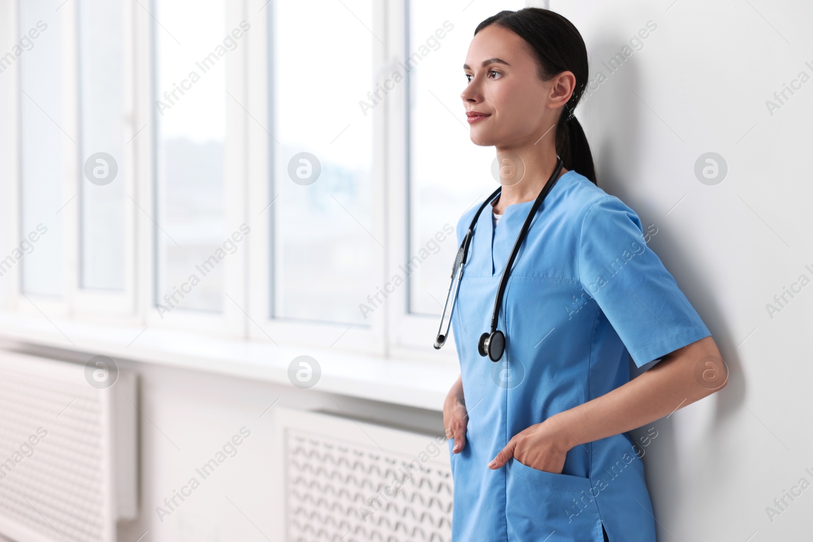 Photo of Portrait of beautiful nurse in clinic. Space for text