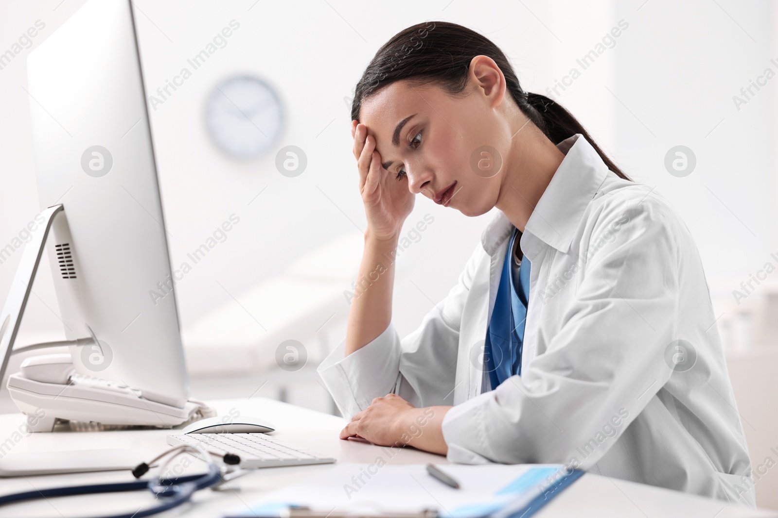 Photo of Tired nurse sitting at table in clinic