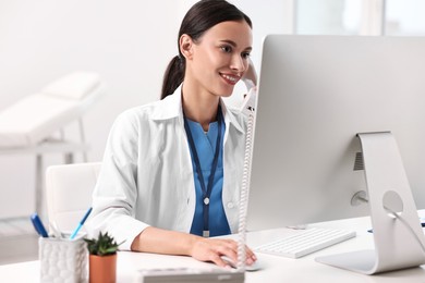 Photo of Smiling nurse consulting patient by phone at table in clinic