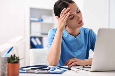 Photo of Tired nurse sitting at table in clinic