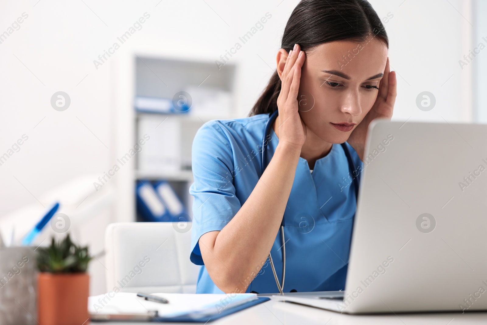 Photo of Tired nurse sitting at table in clinic