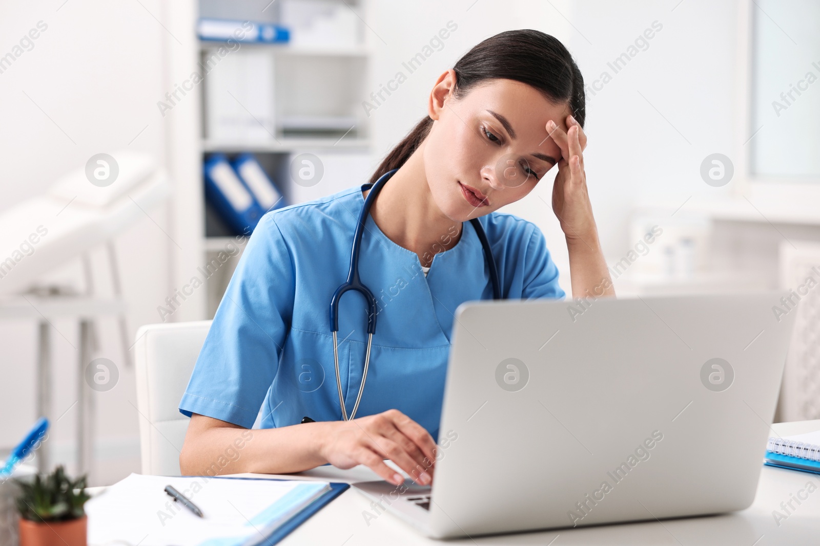 Photo of Tired nurse sitting at table in clinic