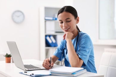 Photo of Smiling nurse working at table in clinic