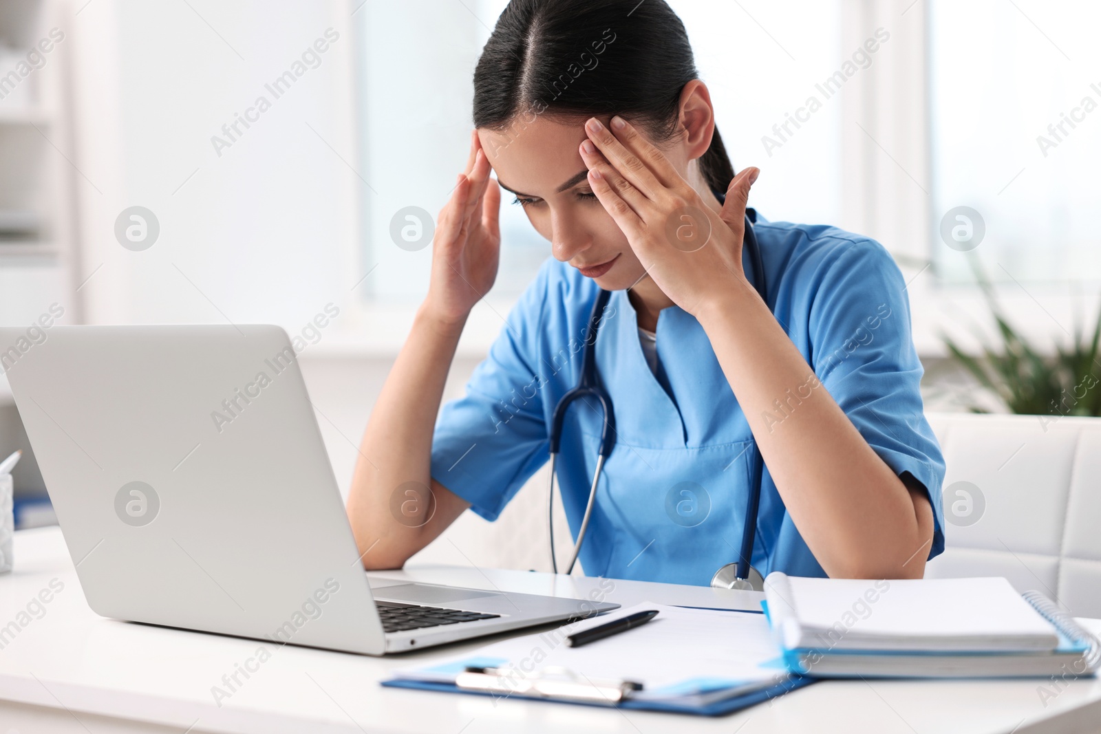 Photo of Tired nurse sitting at table in clinic