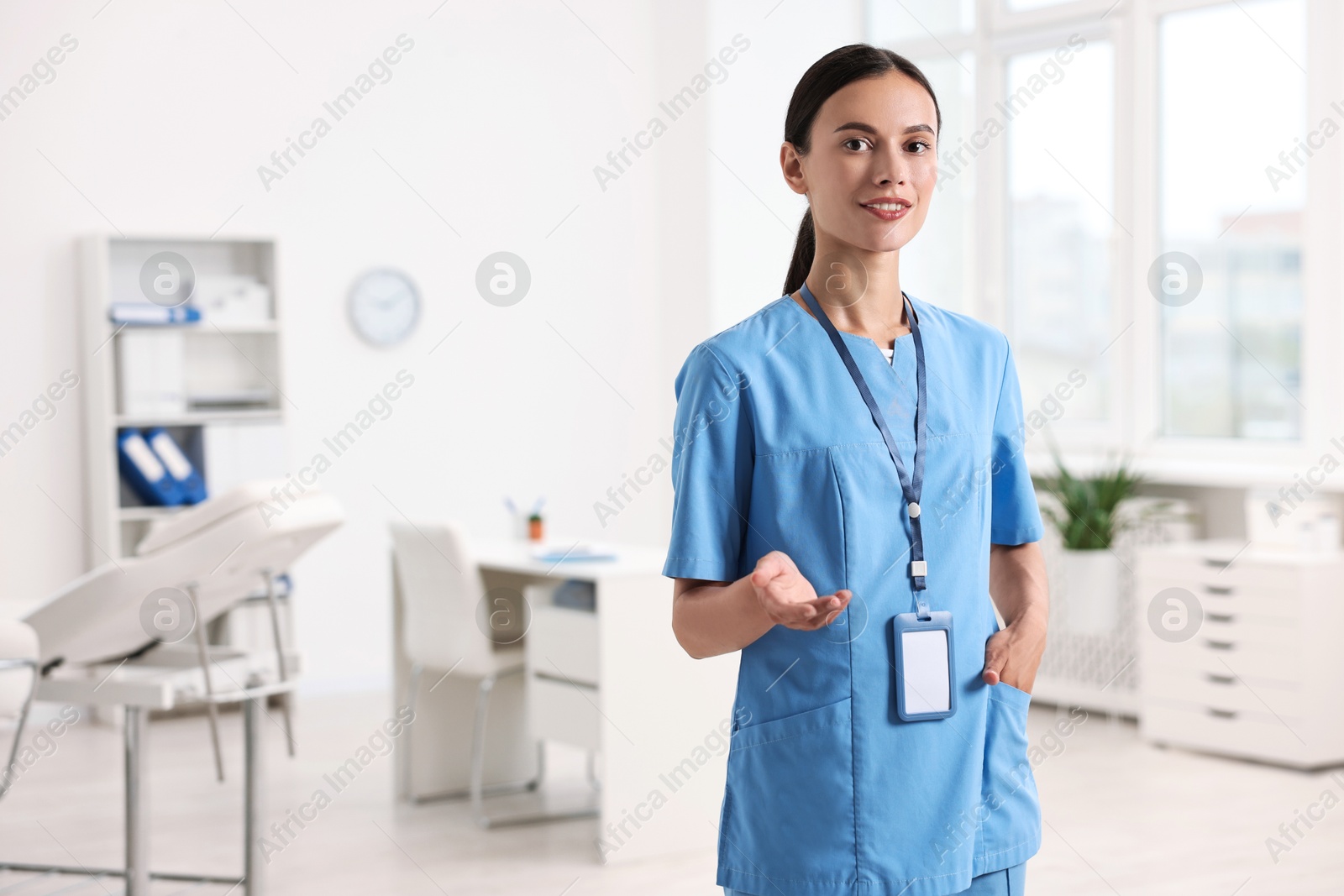 Photo of Smiling nurse holding something in clinic. Space for text