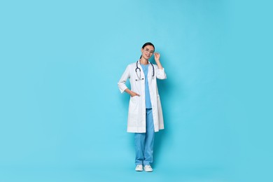 Photo of Smiling nurse in uniform on light blue background