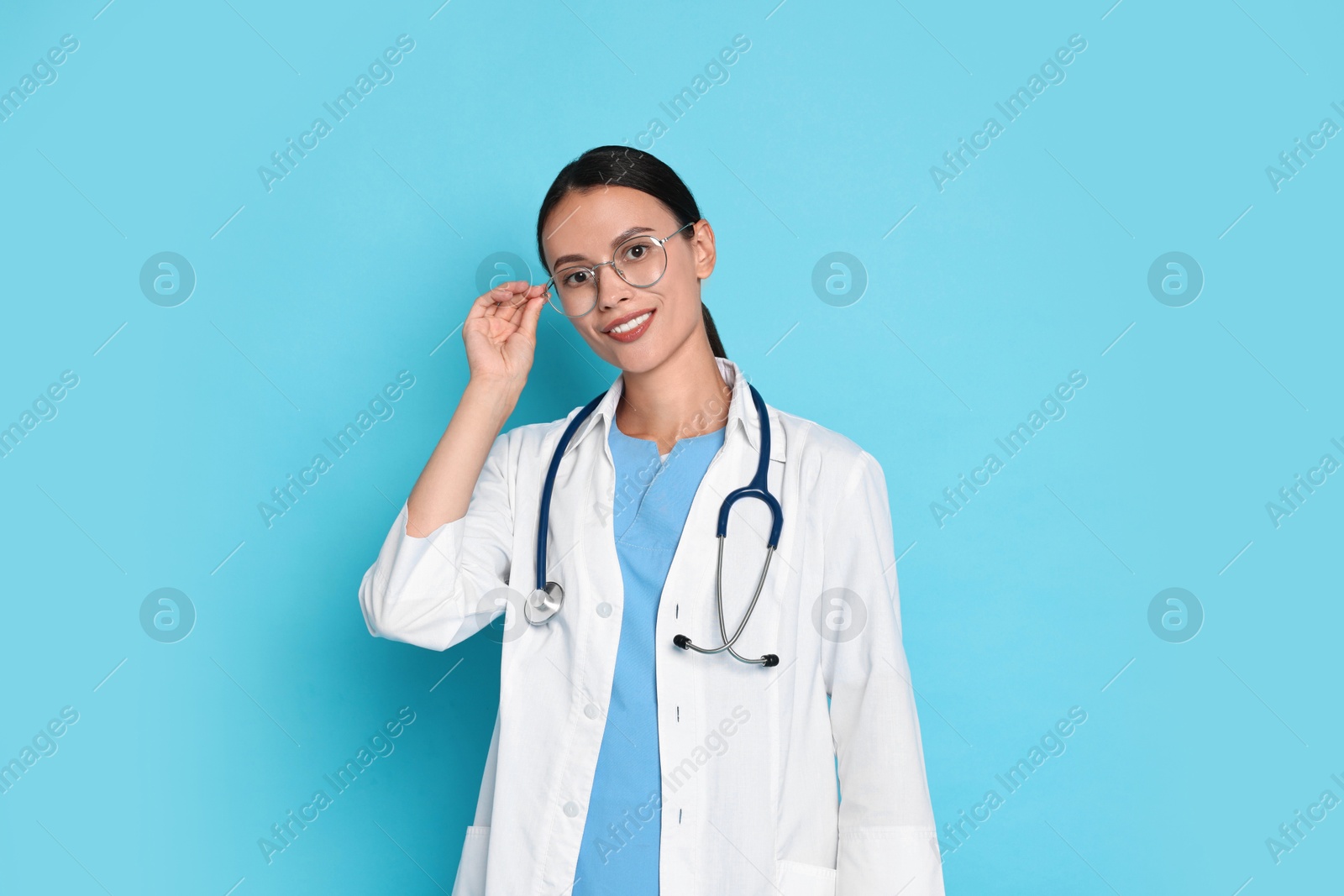 Photo of Smiling nurse in uniform on light blue background