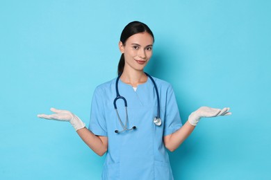 Photo of Beautiful nurse in uniform on light blue background