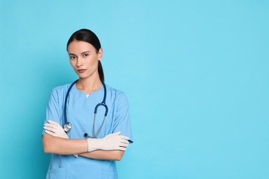 Photo of Beautiful nurse with crossed arms on light blue background. Space for text