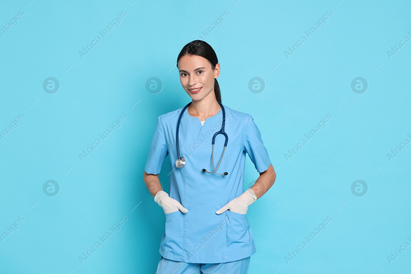 Photo of Smiling nurse in uniform on light blue background