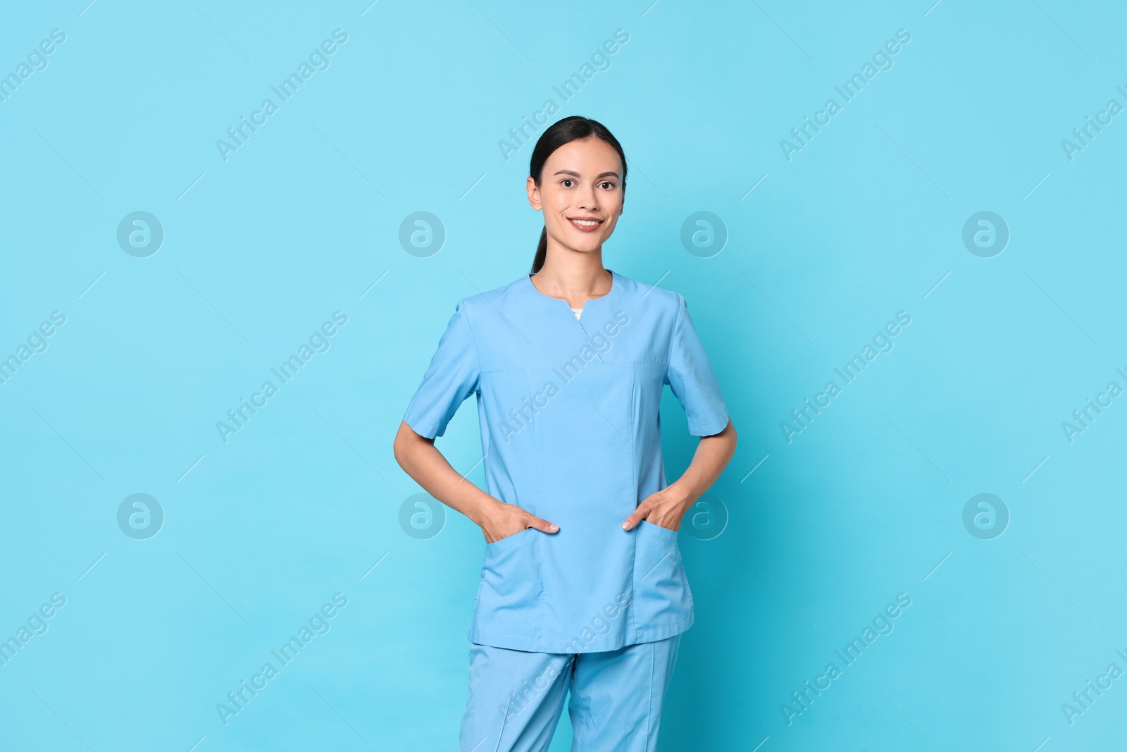 Photo of Smiling nurse in uniform on light blue background