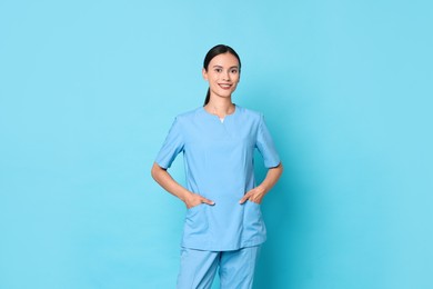 Photo of Smiling nurse in uniform on light blue background